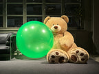 The Original Bigens Ball, 50 in (127 cm), green, next to a giant teddy bear indoors